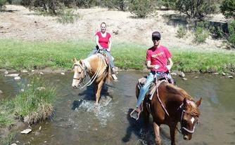 Two riders crossing a creek on horseback